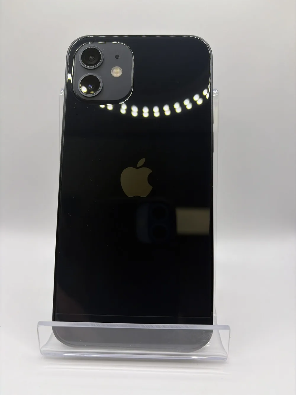 iPhone 12 noir, vu de dos, double capteur photo, posé sur un support transparent