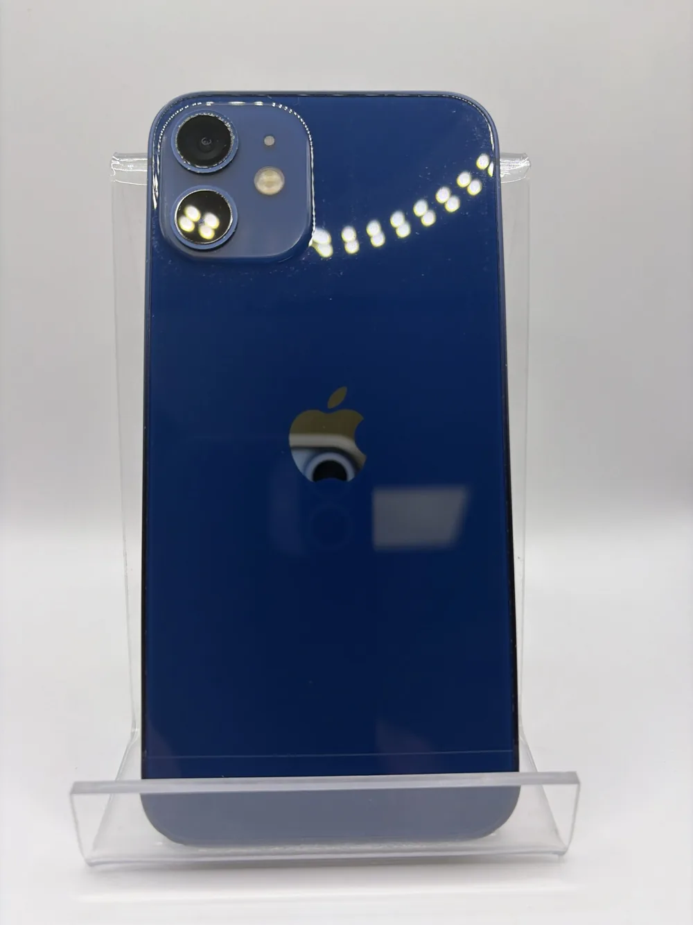 iPhone 12 mini bleu, vu de dos, double capteur photo, posé sur un support transparent