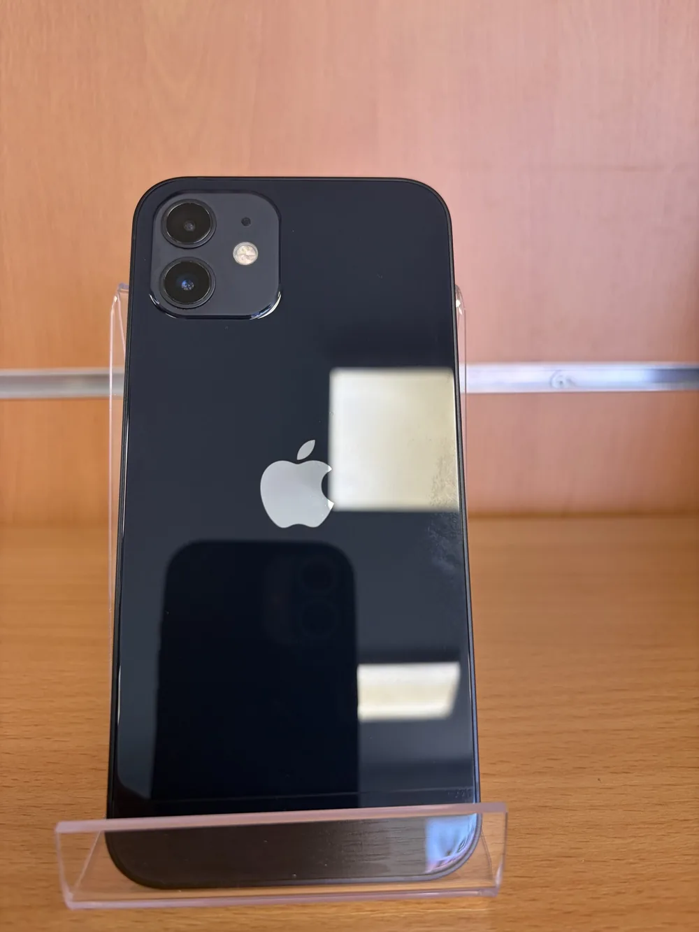 iPhone 12 noir, vu de dos, double capteur photo, posé sur un support transparent