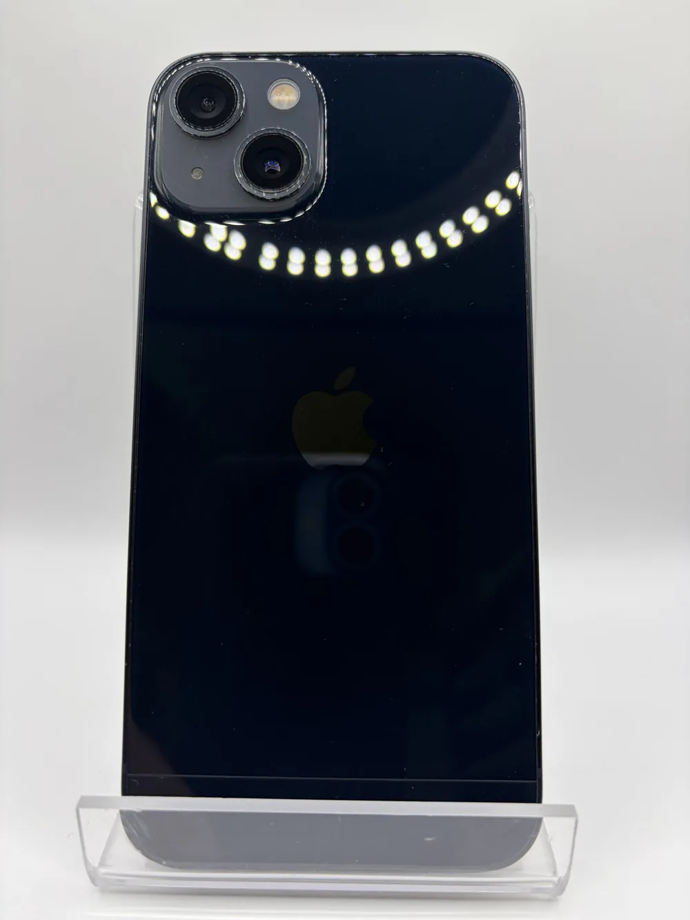 iPhone 13 noir, vu de dos, double capteur photo en diagonale, posé sur un support transparent