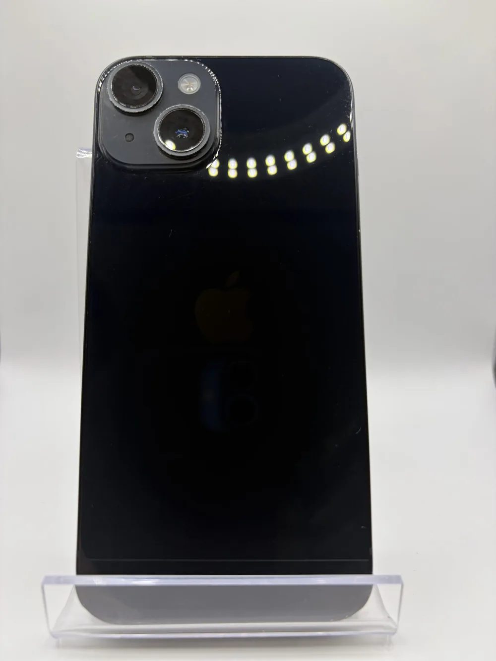 iPhone 14 noir, vu de dos, double capteur photo en diagonale, posé sur un support transparent