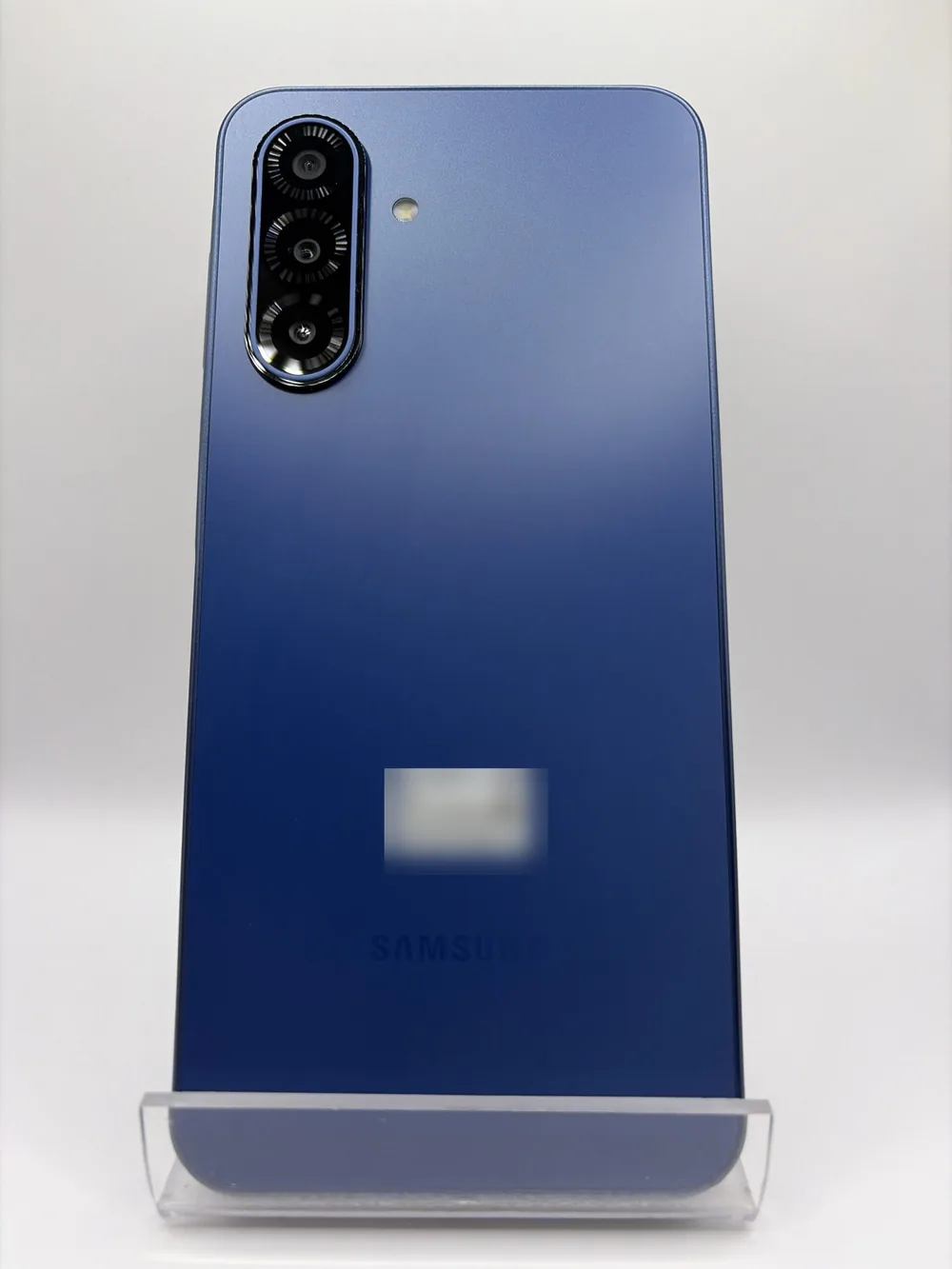 Samsung Galaxy A17 5G bleu, vu de dos, triple capteur photo, posé sur un support transparent