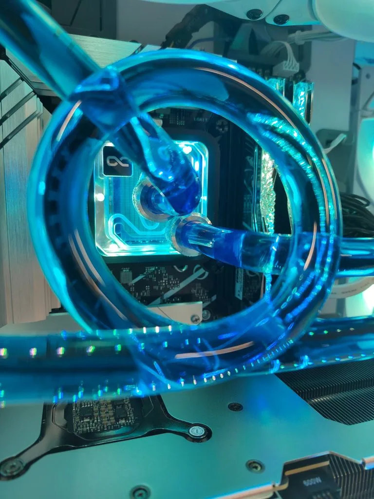 Gros plan sur une boucle de tube souple bleu passant devant un waterblock Alphacool